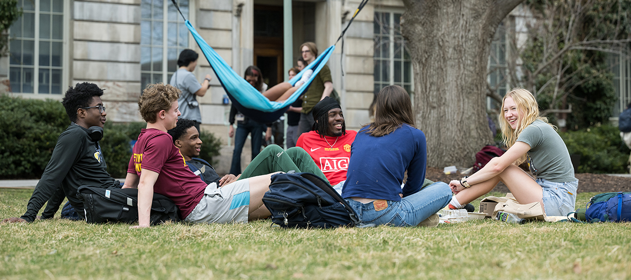 A group of students gathered together on the quad and laughing.