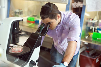 Student examines a sample under a microscope.