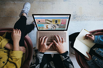 Three people browsing images on a laptop.