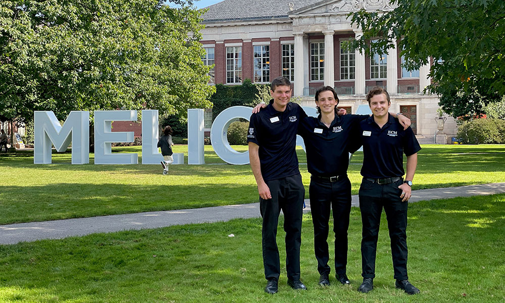 ECM student supervisors celebrate working Commencement in front of the MELIORA letters