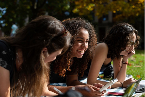 Three people laughing together in a park setting.
