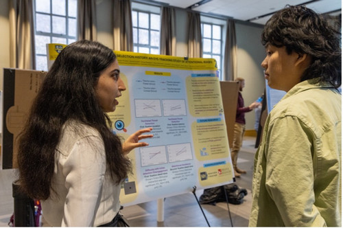 A student explaining their poster to an onlooker.