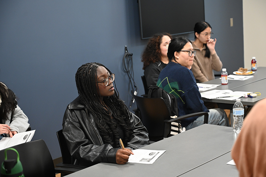 Students sitting at a long table listening.