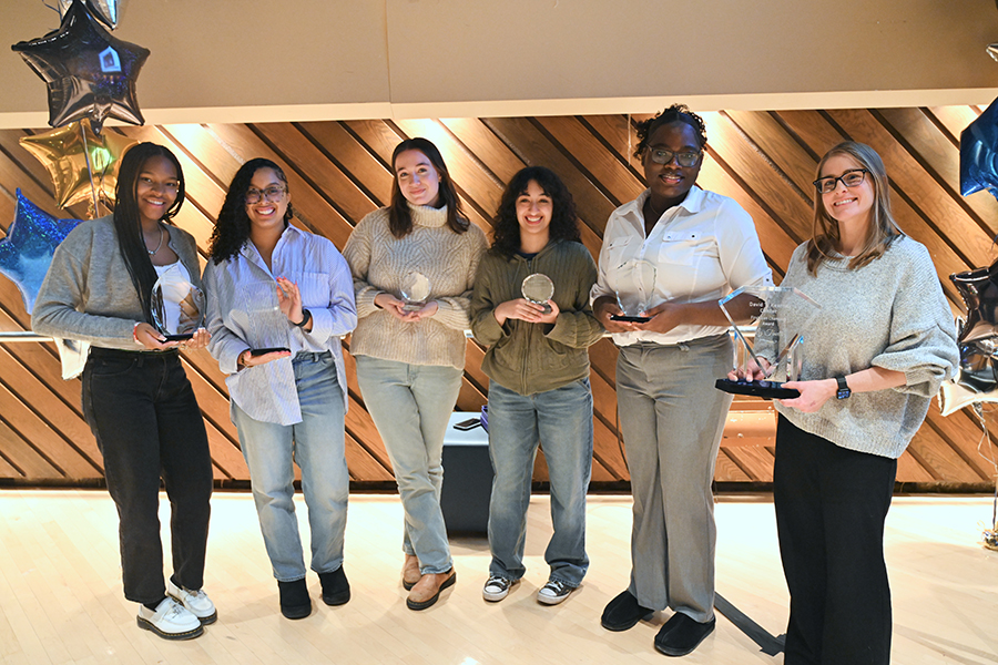 A group of students holding their awards while smiling at the camera.
