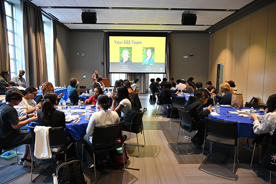 A view of a room full of people facing towards a presentation.