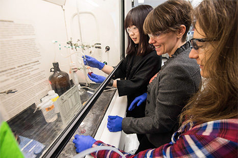 A professor working with two students in a lab.