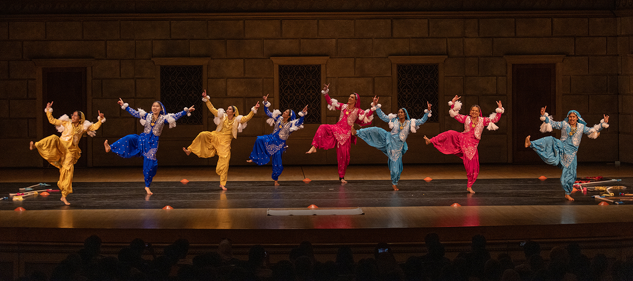 Eight dancers performing a choreographed dance on stage at Kodak Center with colorful attire during the Celebrate Rochester event. 