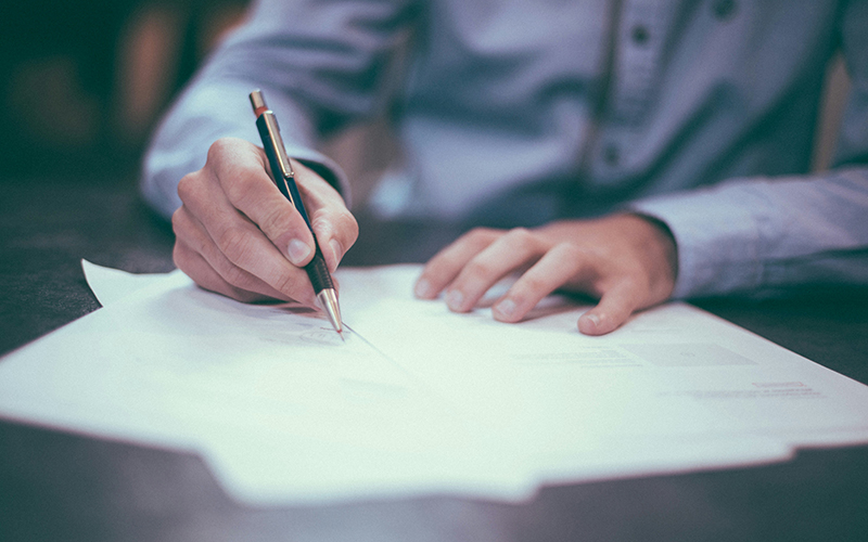 Photo of a person signing paperwork