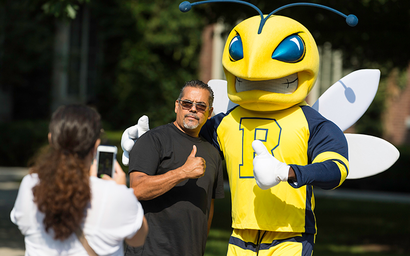 Photo of one parent posing with Rocky while another person takes a photo of them