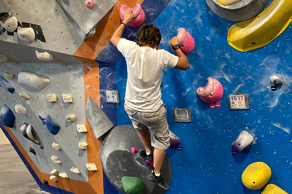 A student makes their way up the indoor climbing wall at Central Rock Gym during the 2025 FOOT program