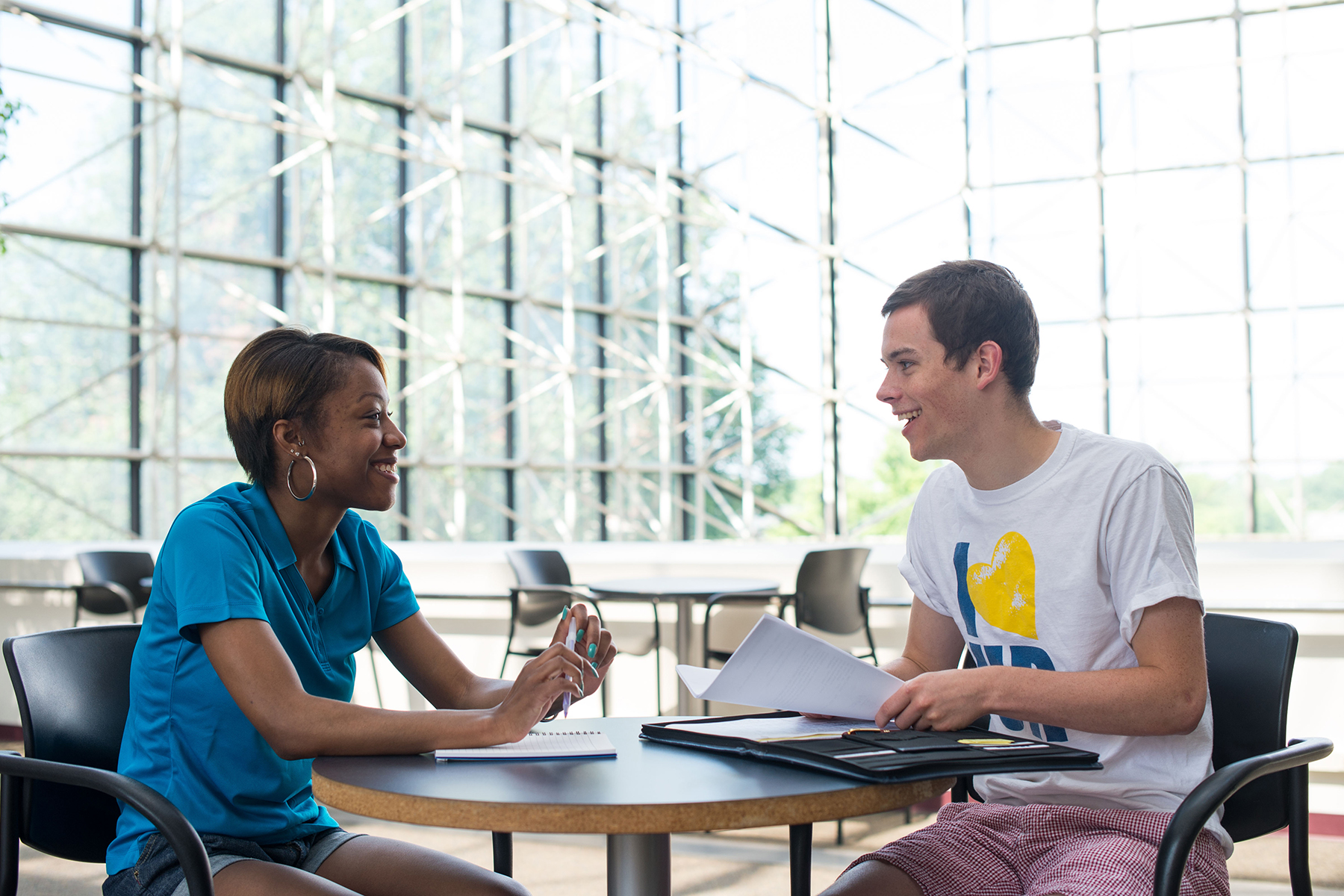 Two students talking while seated at a table