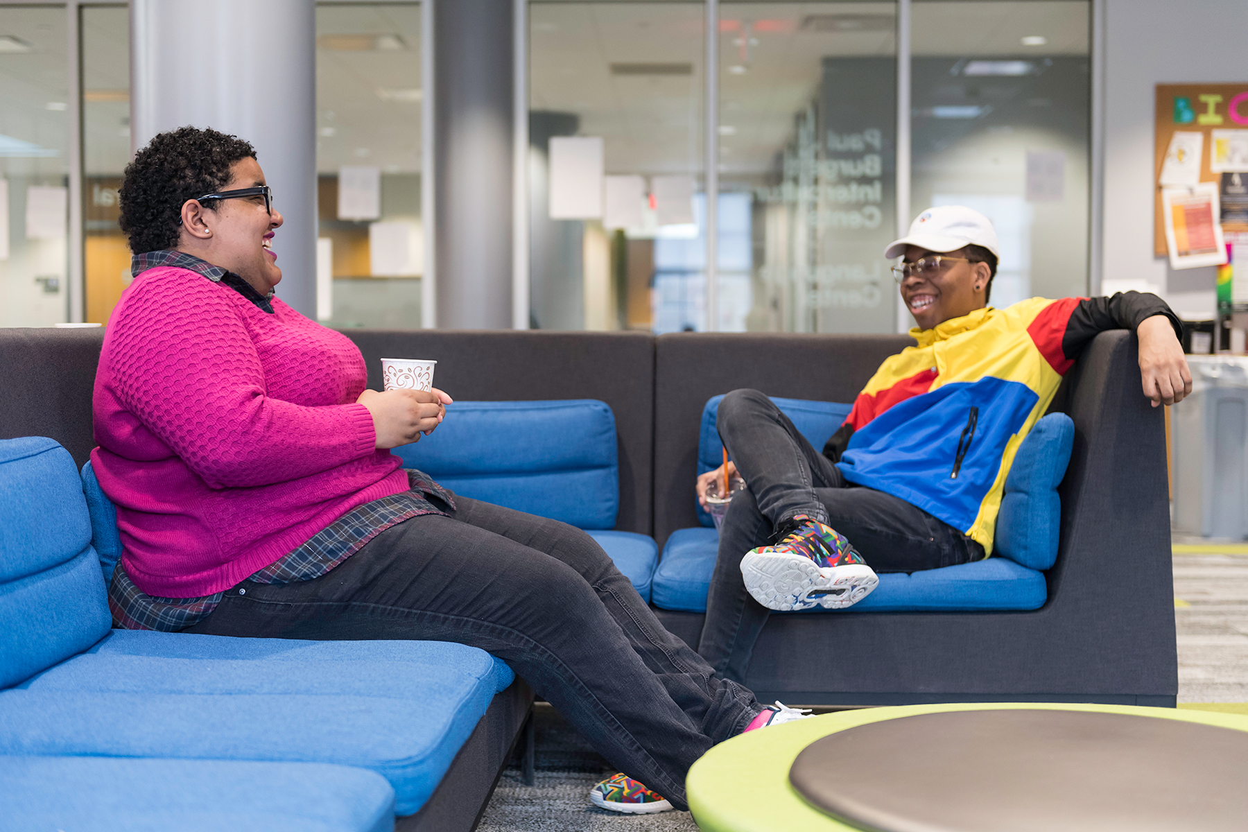 Two students talking and laughing while seated on a couch