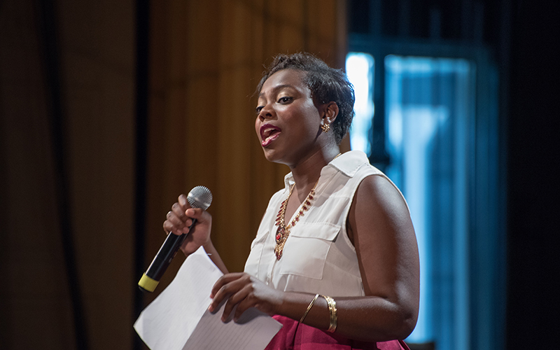 Photo of a female student speaking into a microphone during the One Community program