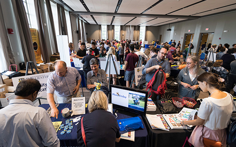Photo of students and staff interacting at tables set up in Feldman Ballroom