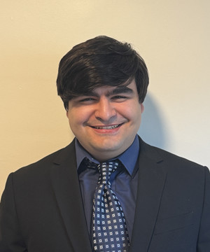 Rafael de Farias smiling in a suit. 