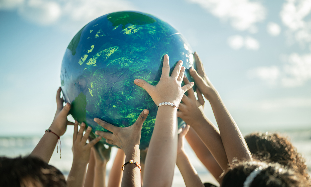 Many hands holding up a globe.