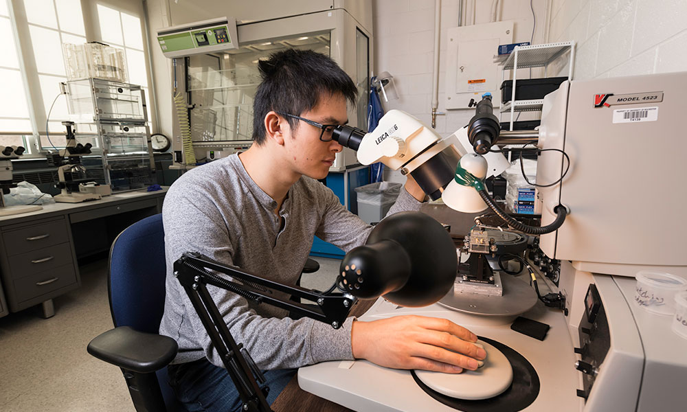A student looking into a microscope in a lab.