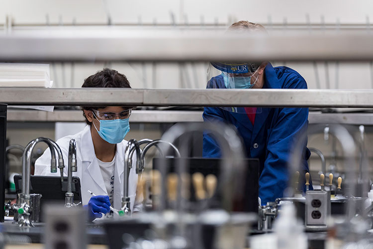 A graduate student helping an undergraduate in a lab.