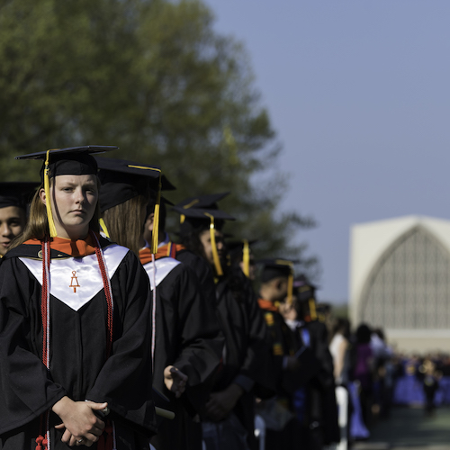 Students wearing ceremonial robes standing on the Eastman Quad