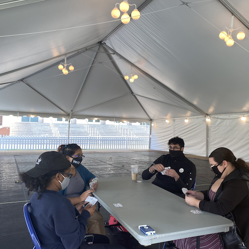 Students sitting at a card table in a tent