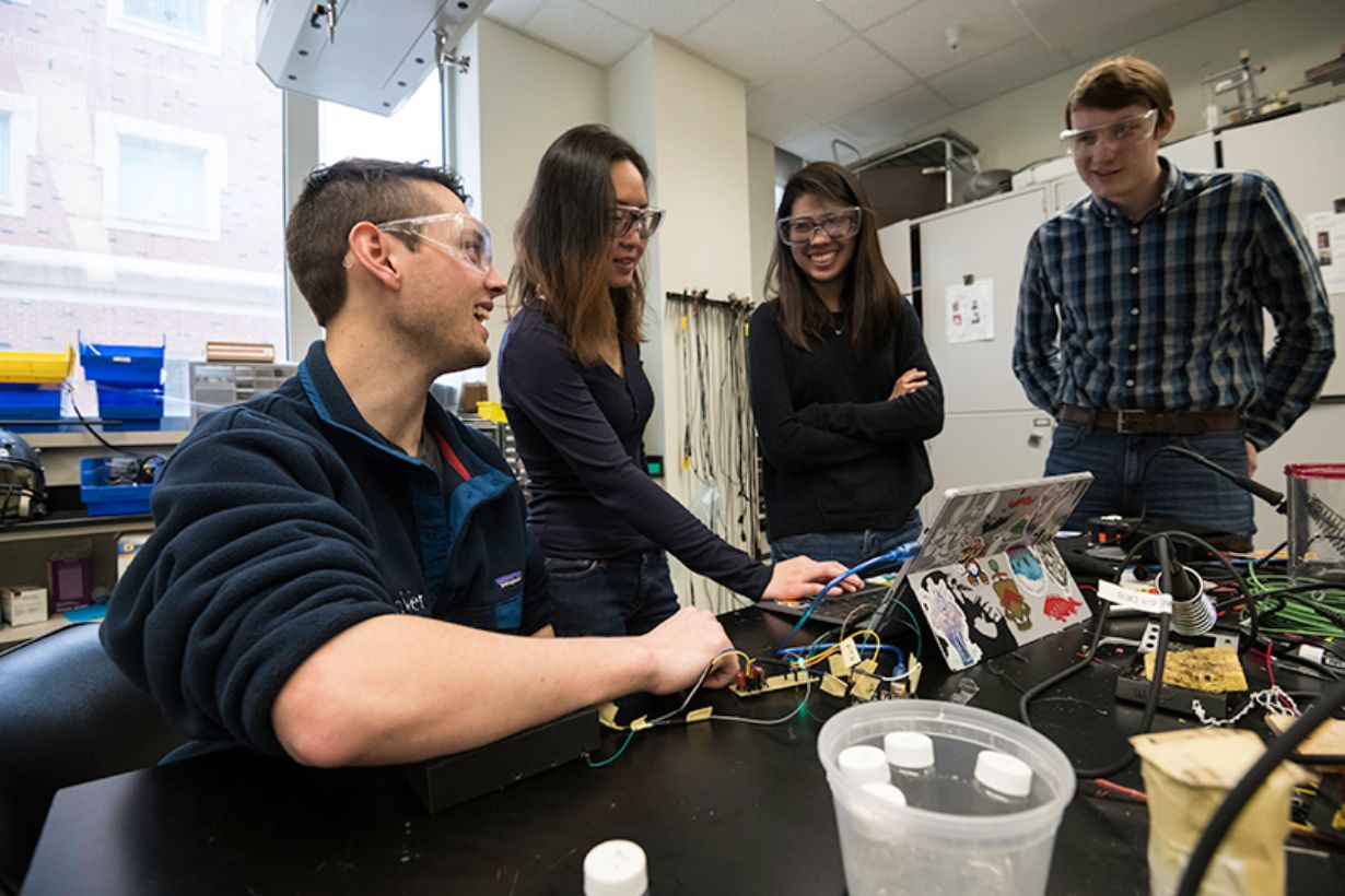 Four students testing a small black device used to screen for diabetes.
