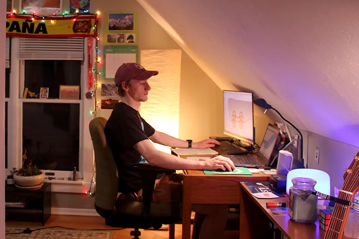 Student sitting in his attic at a computer.