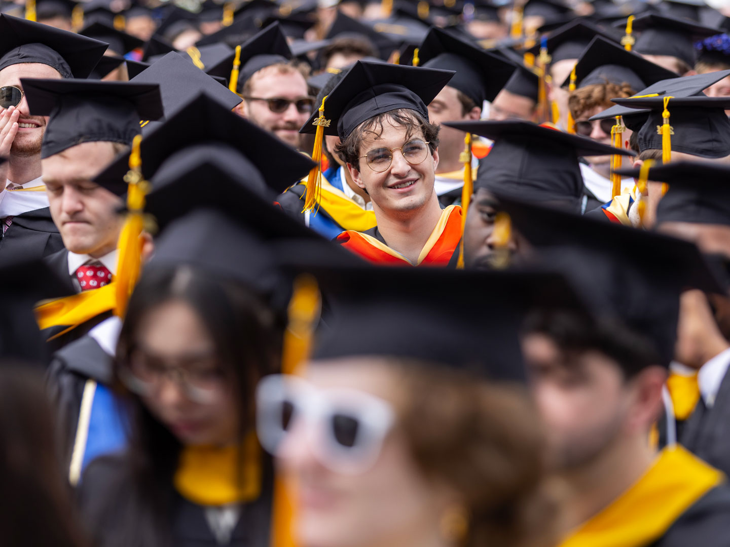 A line of graduates in caps and gowns celebrating during the University of Rochester Commencement Weekend.