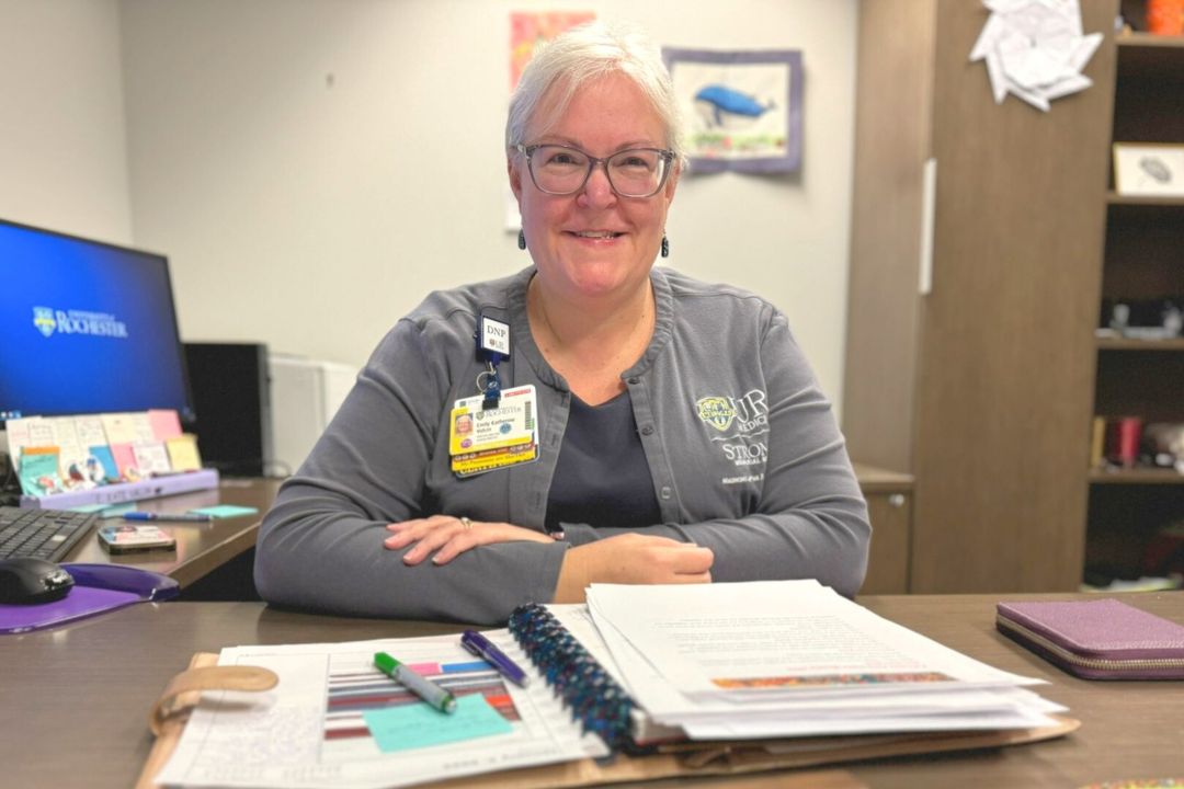 Dr. Valcin sits at her desk with a notebook and pens in front of her.