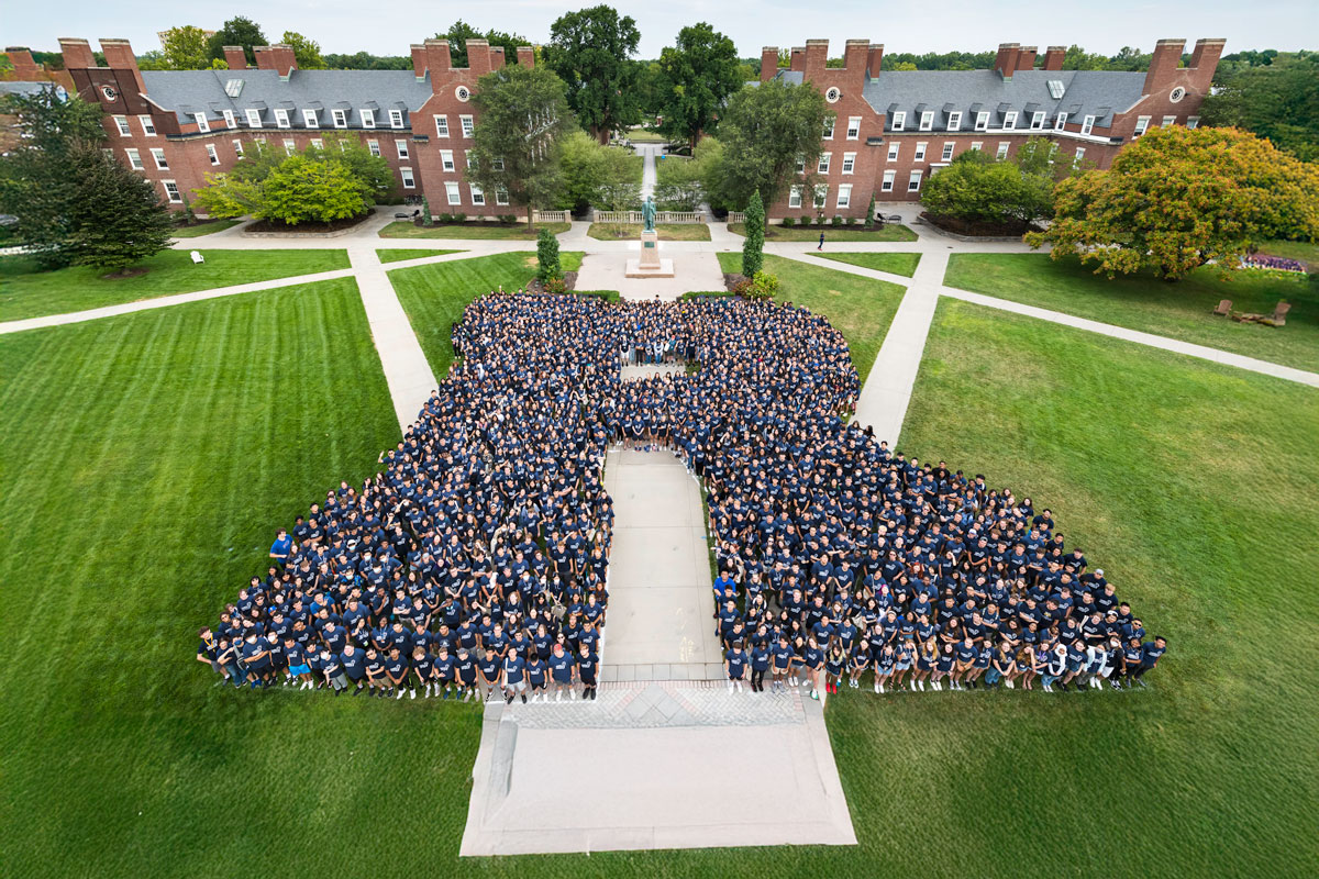 A large group of University of Rochester Class of 2026 students gathered in front of a building, smiling and celebrating.