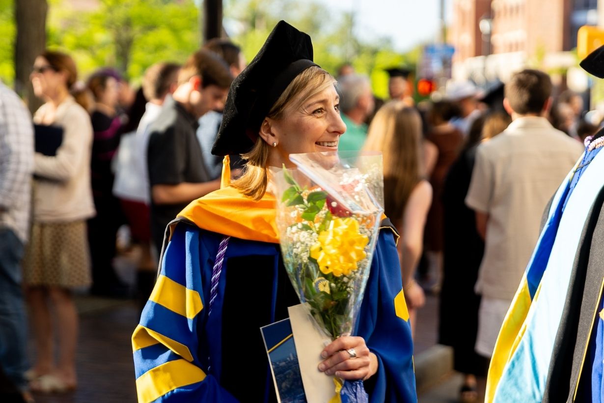 Close-up photo of a doctoral graduate in blue and gold regalia.