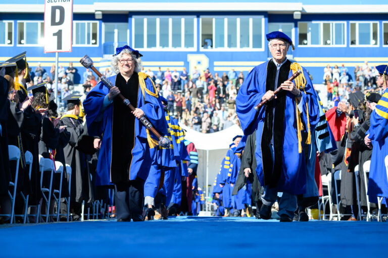 University of Rochester faculty process down the blue carpet carrying ceremonial maces during Commencement Weekend.