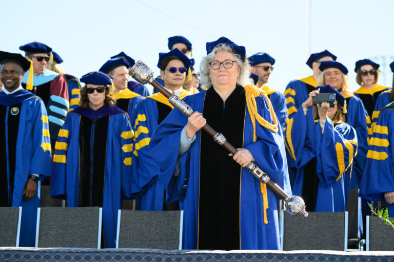 A University of Rochester faculty member holds a ceremonial mace onstage during Commencement Weekend.
