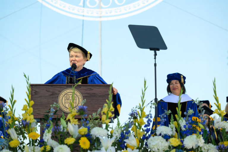 A University of Rochester speaker addresses the Commencement Weekend crowd while another speaker sits onstage