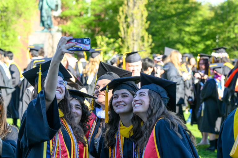 University of Rochester graduates smile together while taking a selfie during Commencement Weekend.