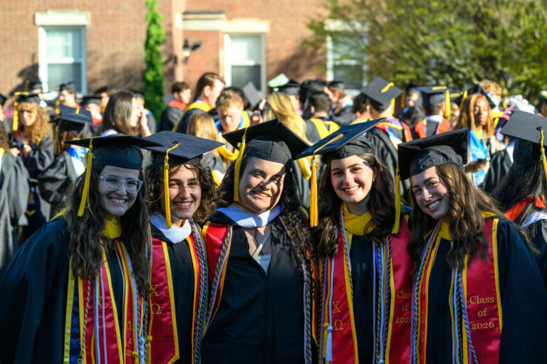 Five University of Rochester graduates pose together in caps and gowns during Commencement Weekend.