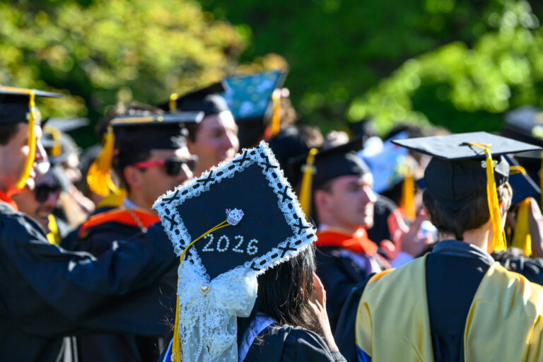 A University of Rochester graduate wears a decorated 2026 cap trimmed with lace and pearls during Commencement Weekend.