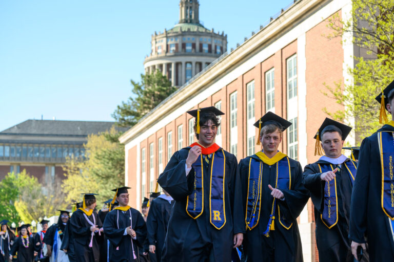 University of Rochester graduates walk in procession with Rush Rhees Library in the background during Commencement Weekend.