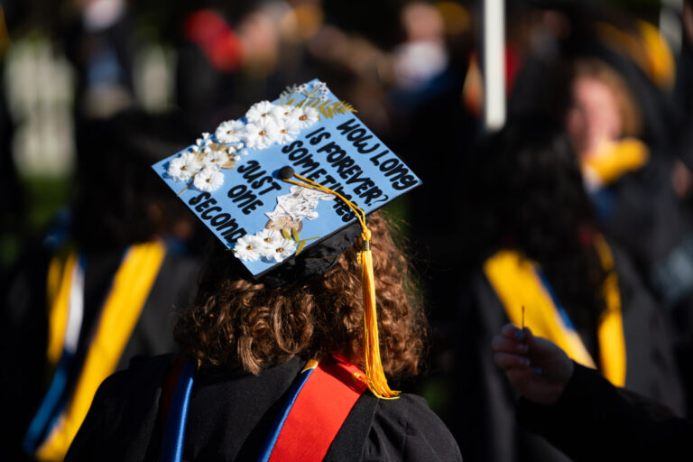 A University of Rochester graduate wears a decorated cap reading You long for eternity somewhere not one second during Commencement Weekend.