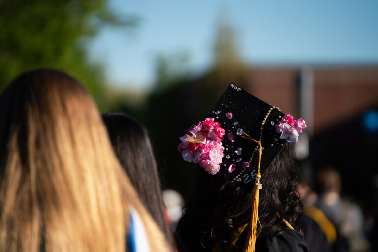 A University of Rochester graduate wears a decorated cap with pink flowers and gems during Commencement Weekend.