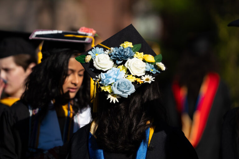 A University of Rochester graduate wears a graduation cap decorated with blue and white flowers during Commencement Weekend.