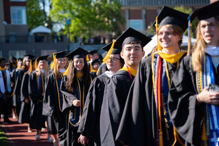 University of Rochester graduates walk in a line during Commencement Weekend.
