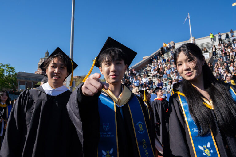 University of Rochester graduates stand together near the stadium seating during Commencement Weekend