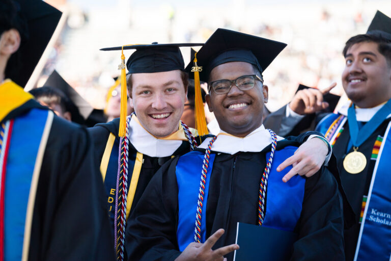 Two University of Rochester graduates smile together during Commencement Weekend.