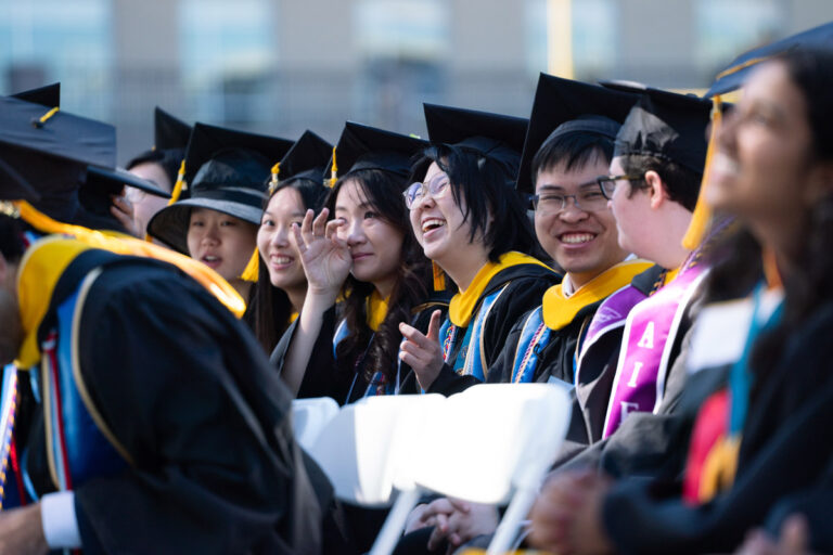 University of Rochester graduates laugh and talk together during the Commencement Weekend ceremony.