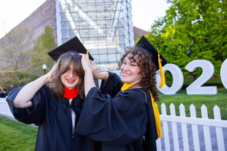 A University of Rochester graduate adjusts his academic hood before the Commencement Weekend ceremony.