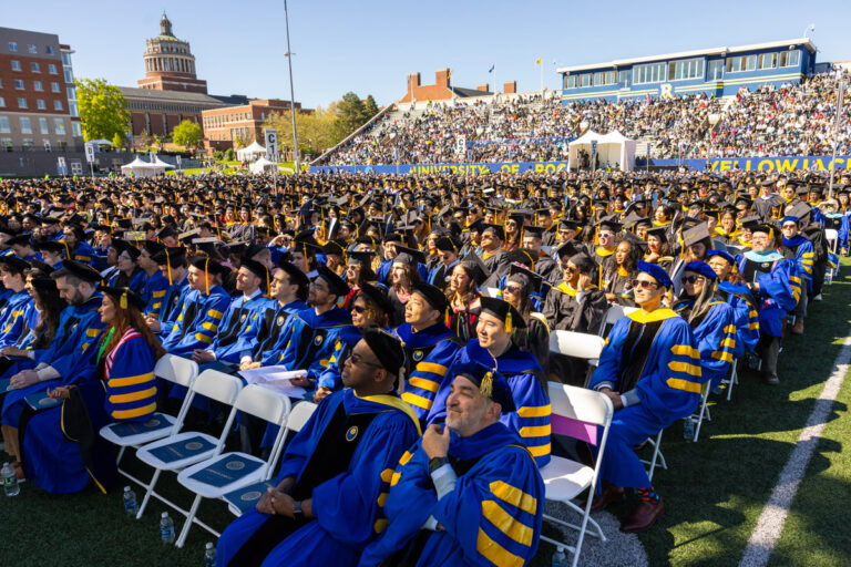 Wide shot of University of Rochester graduates, faculty, and guests gathered at Fauver Stadium for the Commencement Weekend ceremony.