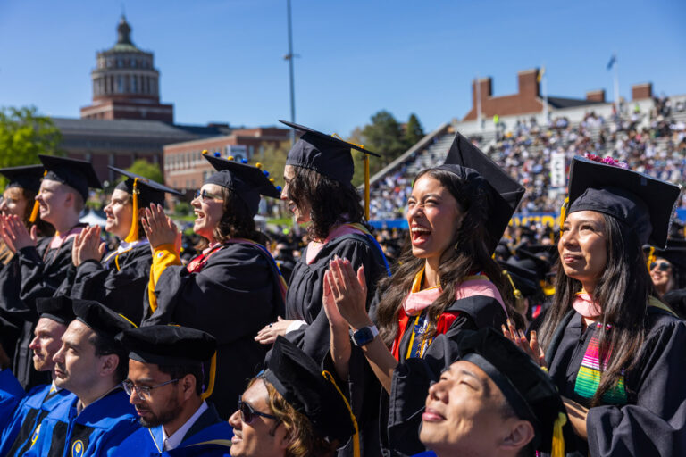 University of Rochester graduates cheer and applaud during the Commencement Weekend ceremony at Fauver Stadium.
