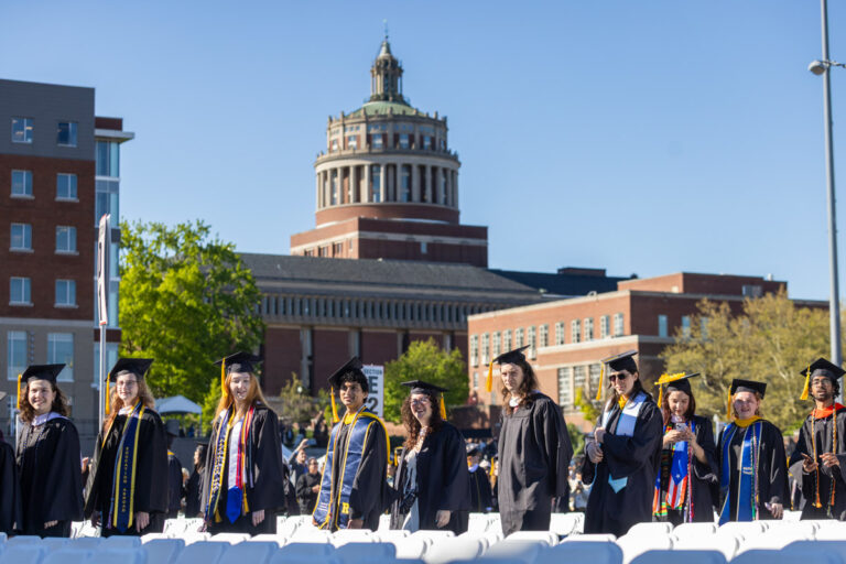 University of Rochester graduates line up near the stage with Rush Rhees Library in the background during Commencement Weekend.