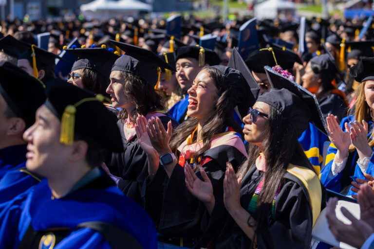 University of Rochester graduates applaud and smile during the Commencement Weekend ceremony.
