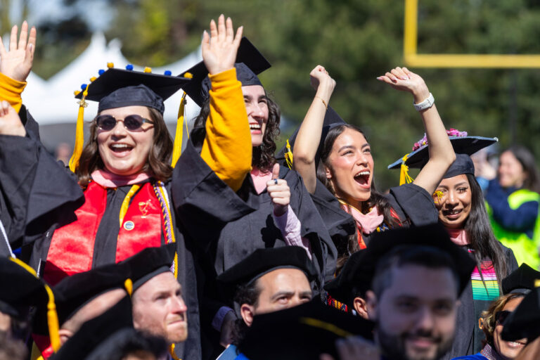 University of Rochester graduates smile and celebrate in a packed Fauver Stadium during Commencement Weekend.